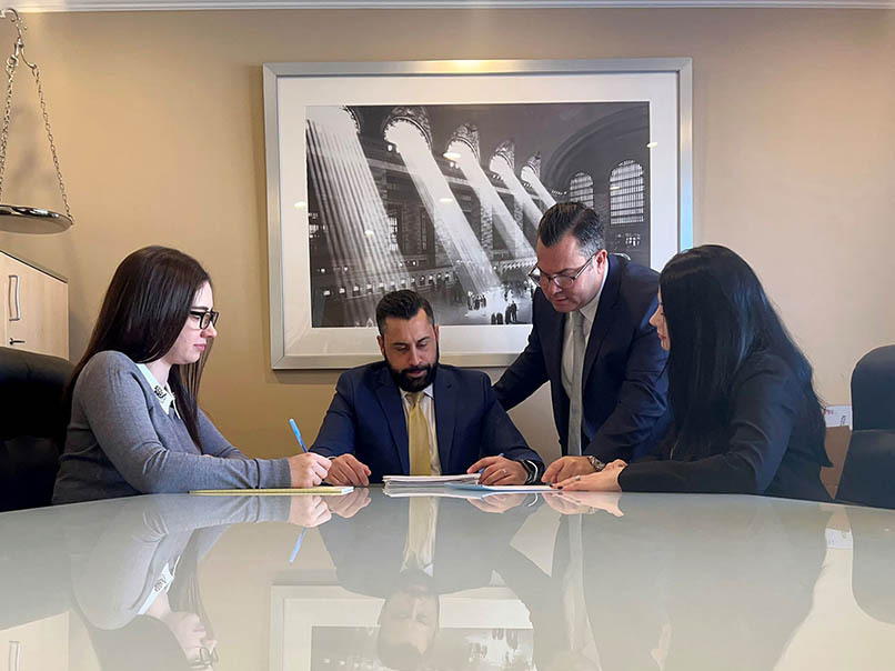 Closing attorney consulting with clients at a real estate closing table reviewing and signing documents.